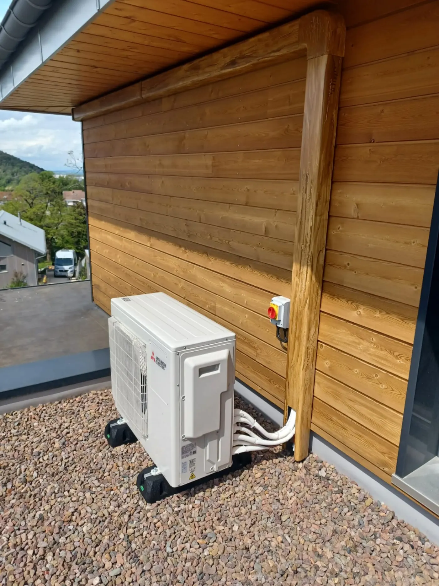Unité extérieure de climatisation réversible Mitsubishi installée sur un chalet en bois